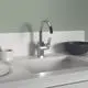 Küchenarmatur mit auslaufendem Rohr in chrom, montiert an einer weißen Arbeitsplatte. Im Hintergrund sind Geschirr und eine Schüssel sichtbar. Ideal Standard Produkt.